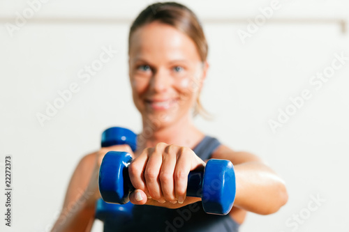 Frau macht Sport mit Hantel im Fitnessstudio