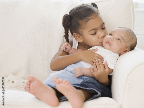 African girl kissing baby sibling photo