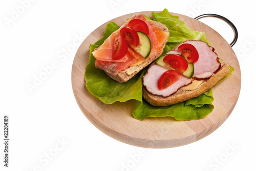 Two sandwiches with ham, smoked salmon and tomato.