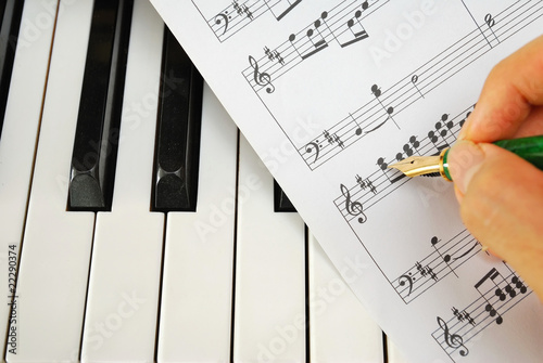 Writing on music score with pen on piano keyboard