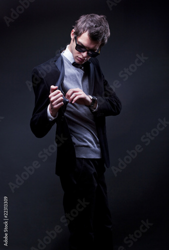 attractive young man wearing elegant black suit and sunglasses