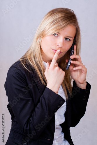 Business woman with mobile phone and finge on mouth