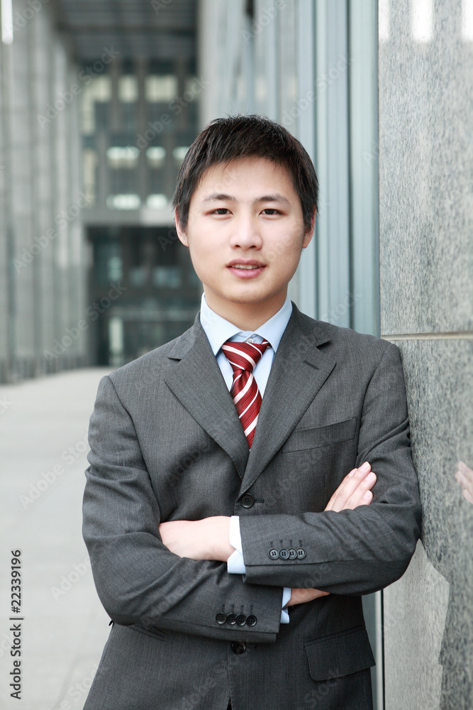 a yong Asiatic businessman is standing outdoor a yong Asiatic businessman is standing outdoor