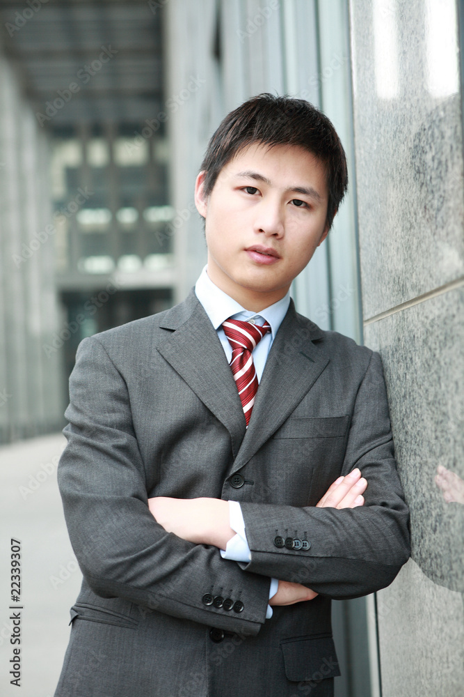 a yong Asiatic businessman is standing outdoor a yong Asiatic businessman is standing outdoor