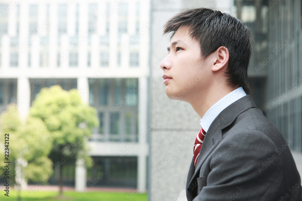 a yong Asiatic businessman is standing outdoor a yong Asiatic businessman is standing outdoor
