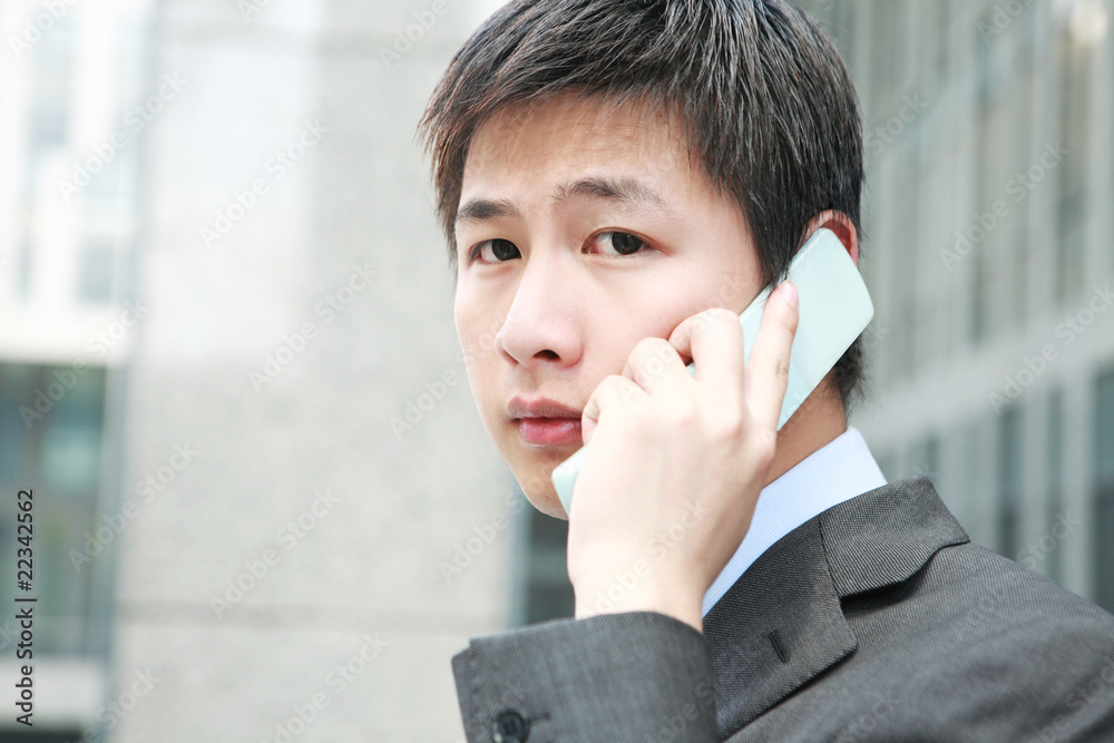 a yong Asiatic businessman is answering phone outdoor a yong Asiatic businessman is answering phone outdoor