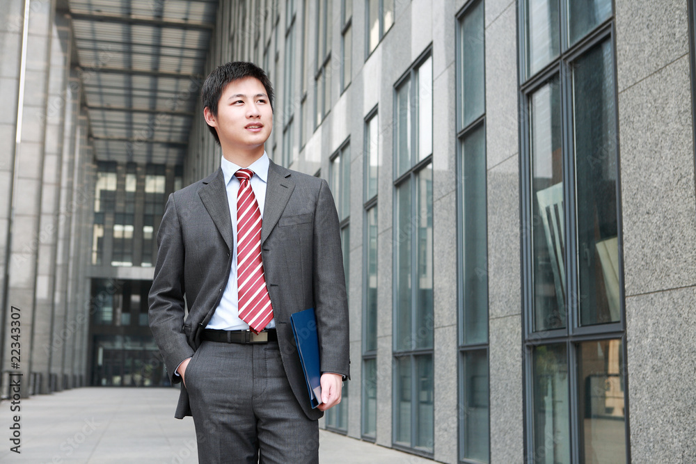 a yong Asiatic businessman is walking outdoor a yong Asiatic businessman is walking outdoor