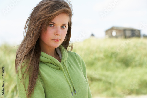 Thoughtful Young Woman Standing On Beach Wearing Hooded Top With