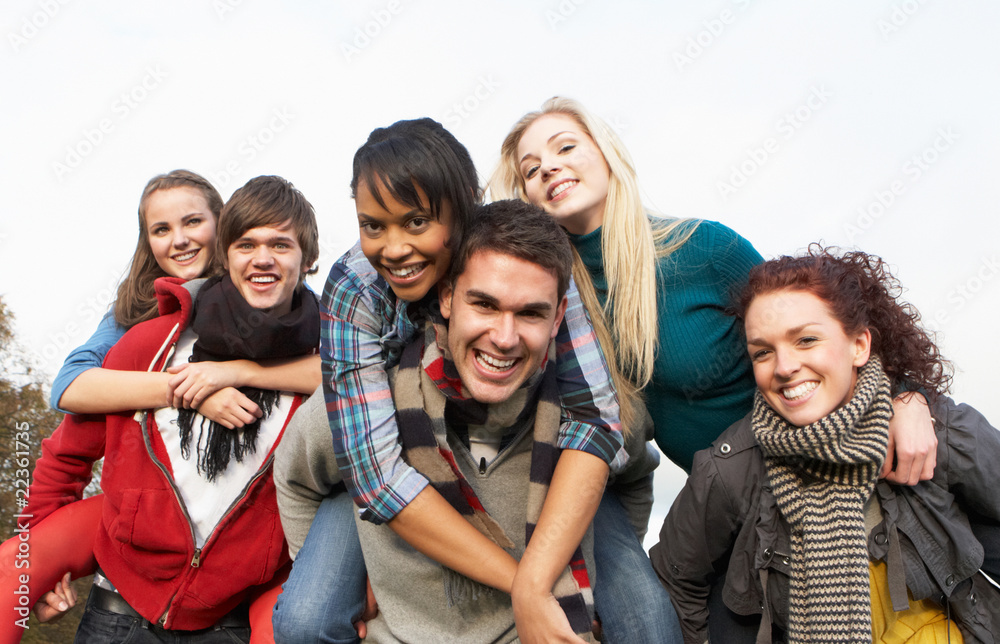 Fototapeta premium Group Of Teenage Friends Having Piggyback Rides In Autumn Landsc