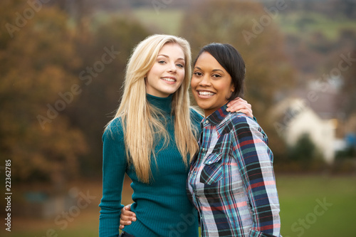 Two Female Teenage Friends On Walk In Autumn Landscape