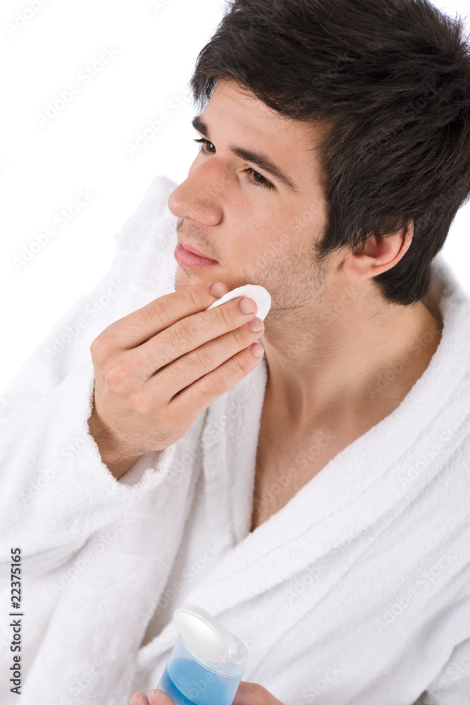 Facial care - Young man cleaning face with lotion Facial care - Young man cleaning face with lotion