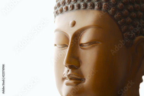 Close up of Buddha head carving against white background