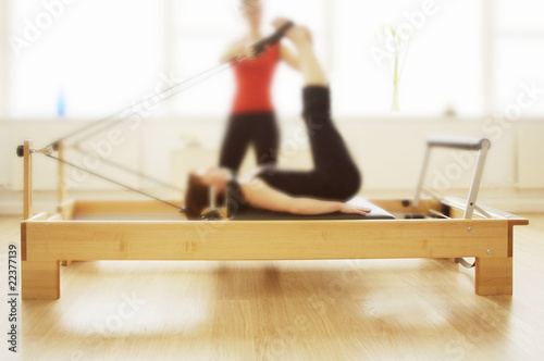 Plilates reformer in use by two women, soft focus