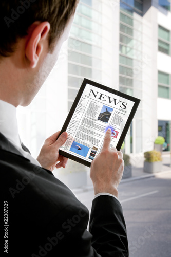 Businessman holding a touchpad pc, reading a newspaper