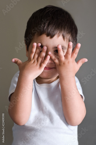 bambino che gioca con le mani in viso