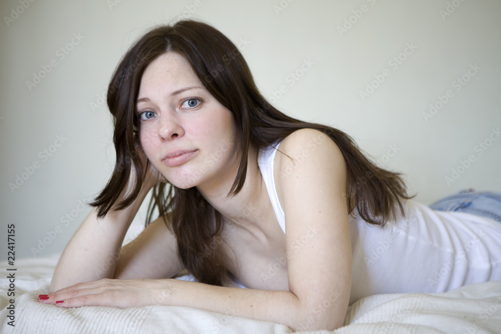 smiling young woman in white lying on bed smiling young woman in white lying on bed
