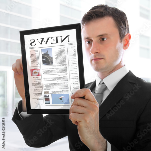 Businessman holding a touchpad pc, reading a newspaper