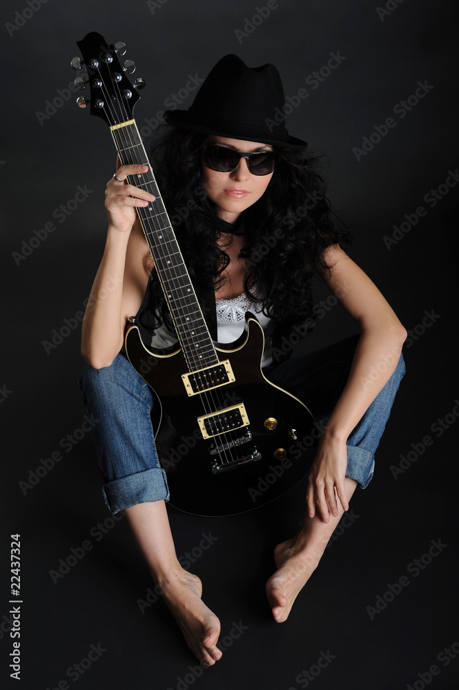 Girl in sunglasses sitting on the floor with a guitar