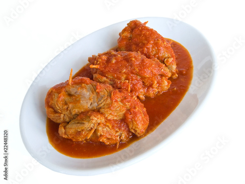 Meat roulade in tomato sauce on white dish.