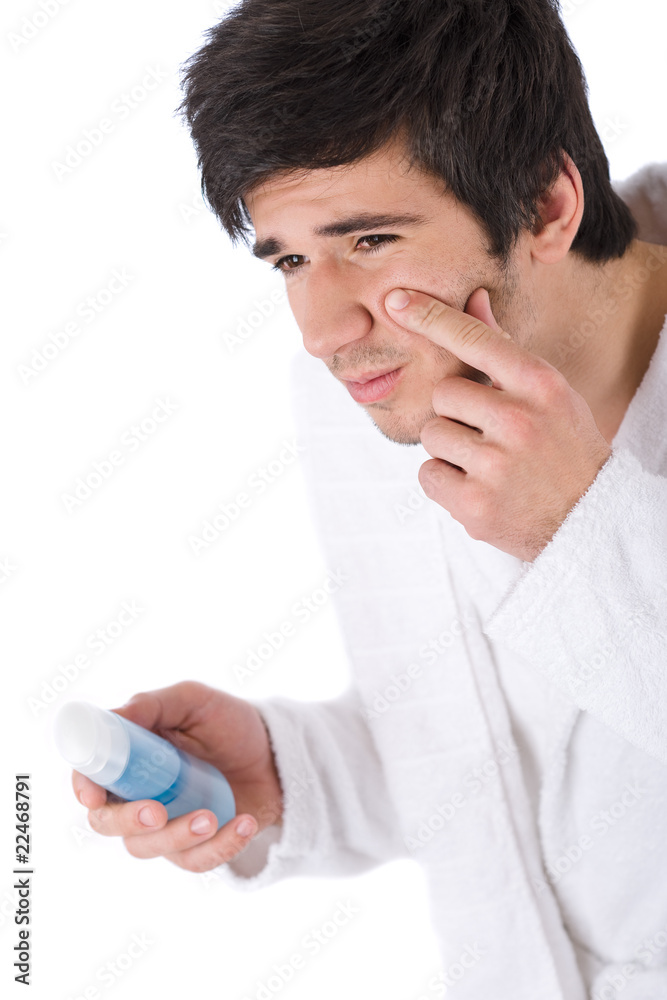 Facial care - Young man cleaning face with lotion Facial care - Young man cleaning face with lotion