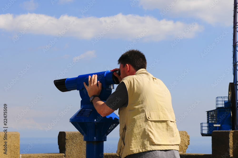 Man looking through a coin operated binoculars