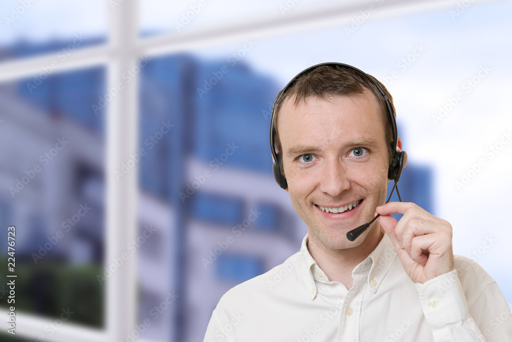 Businessman smiling talking with headset near a window Businessman smiling talking with headset near a window