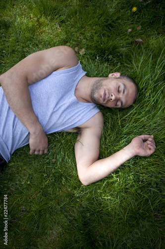 Jeune homme sportif en repos dans l'herbe