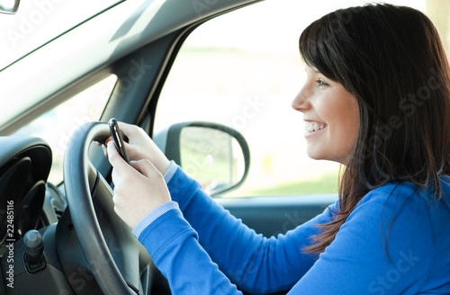 Smiling teen girl using a mobile phone while driving