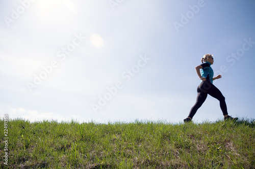 Young woman running outdoors on green trail