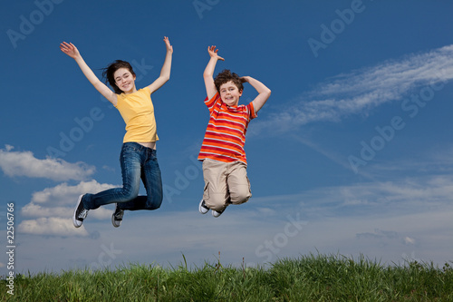 Girl and boy jumping  running against blue sky
