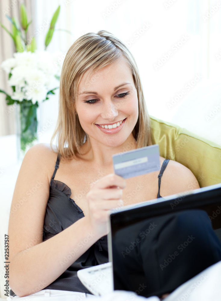 Attractive blond woman shopping on-line sitting on a sofa Attractive blond woman shopping on-line sitting on a sofa