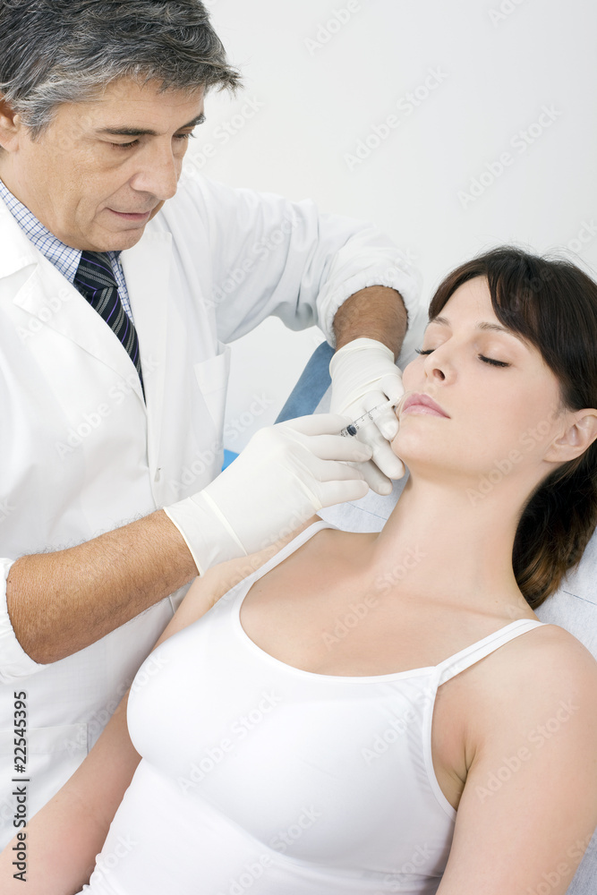 Young woman receives cosmetic injection from doctor Young woman receives cosmetic injection from doctor