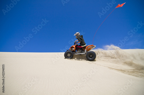 Large sand spray from ATV quadbike rider in the dunes