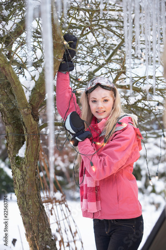 Teenage Girl Hanging Fairy Lights In Tree With Icicles In Foregr photo