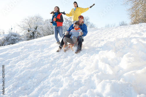 Family Having Fun Sledging Down Snowy Hill