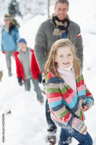 Family Enjoying Walk Through Snowy Landscape