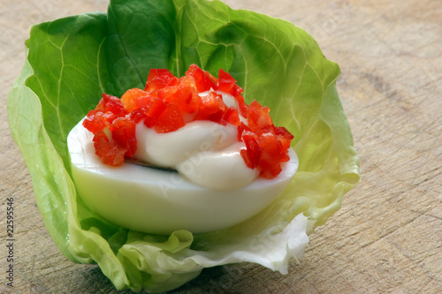 Pikante Eihälfte auf einem Salatblatt mit Paprika