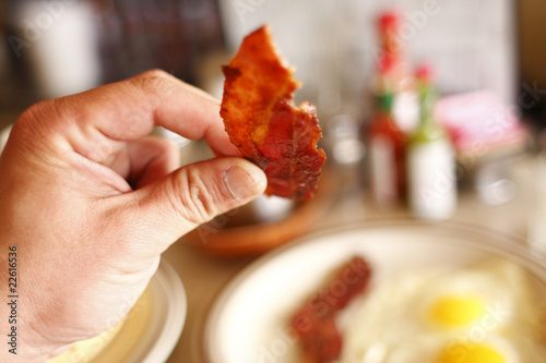 Eating a piece of bacon with breakfast