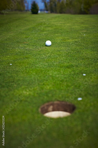 Single golf ball beside the hole on the golf course
