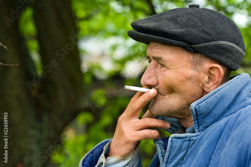 Poor old man smoking outdoors