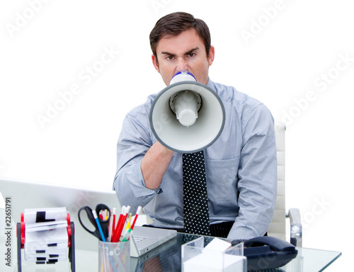 Furious businessman yelling through a megaphone sitting at his d photo