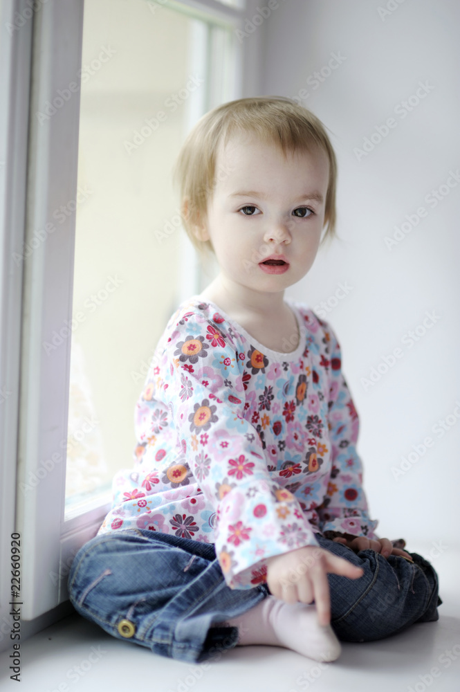 Two years old girl sitting by the window