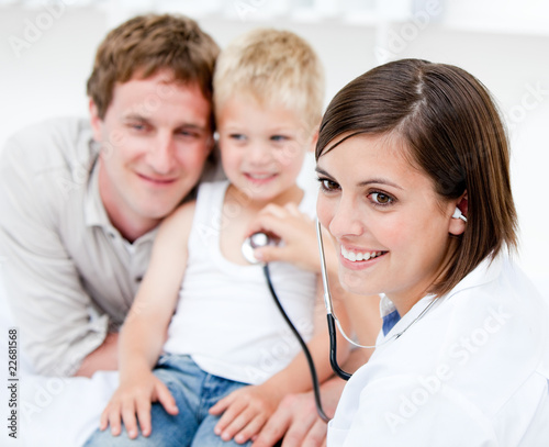 Beautiful female doctor examining a little boy with his father