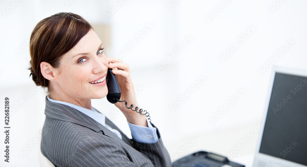 Smiling businesswoman on phone sitting at her desk Smiling businesswoman on phone sitting at her desk