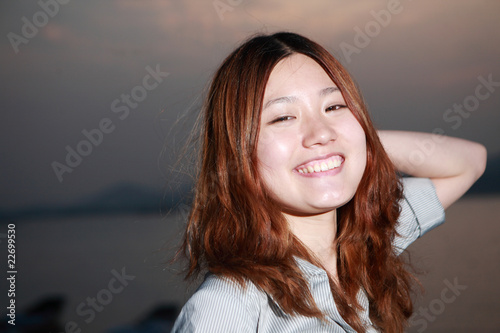 Beautiful young woman on the beach at sunset .