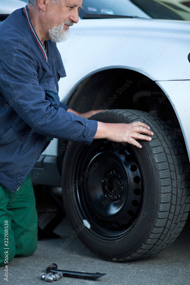 mechanic changing a wheel of a modern car (color toned image) mechanic changing a wheel of a modern car (color toned image)