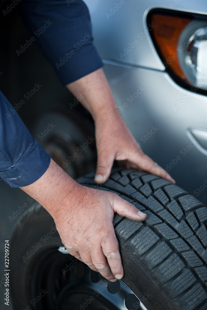 mechanic changing a wheel of a modern car (color toned image)