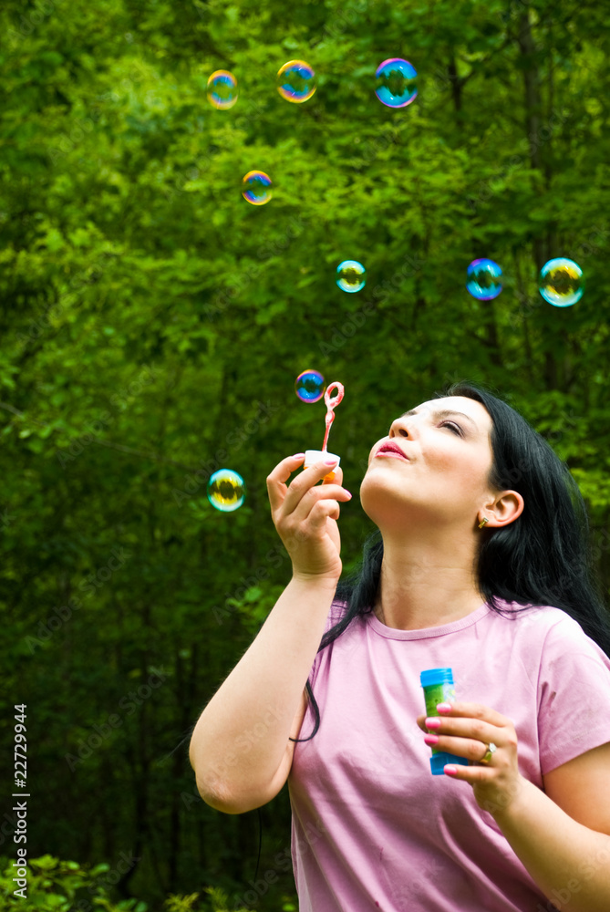 Woman blowing colorful soap bubbles