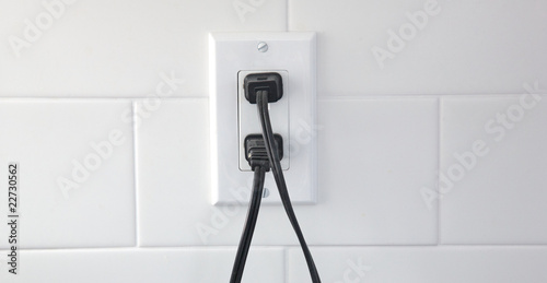 Two plugs in an outlet set against a tile backsplash