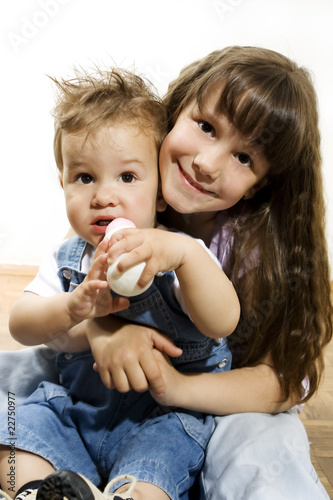 Photos Cute little girl holding baby brother in her lap.